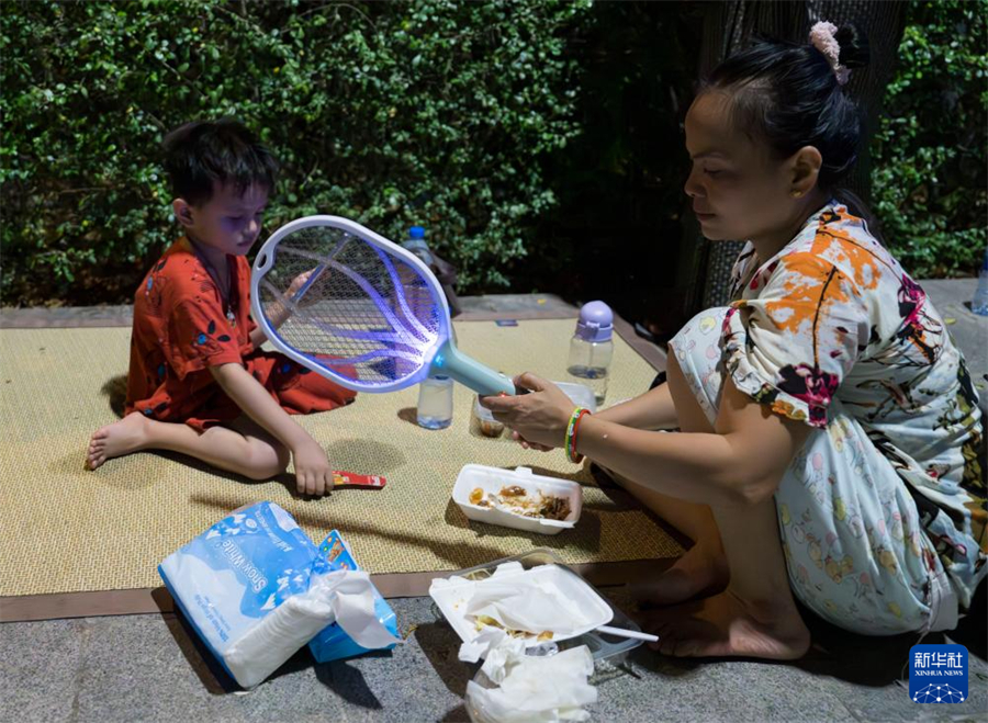3月31日，在緬甸曼德勒街頭，一名女子用電蚊拍為孩子驅(qū)趕蚊蟲。新華社記者 才揚(yáng) 攝