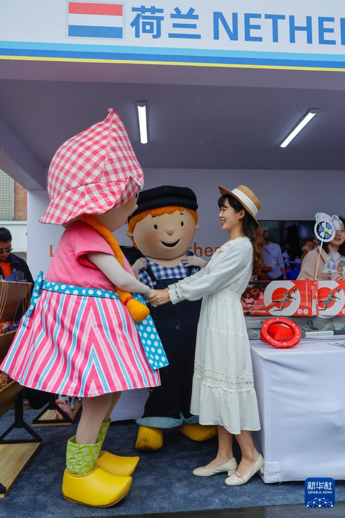 4月12日，參觀者（右）在荷蘭展臺與兩名裝扮成卡通人物的演員跳舞互動。新華社記者 沈伯韓 攝
