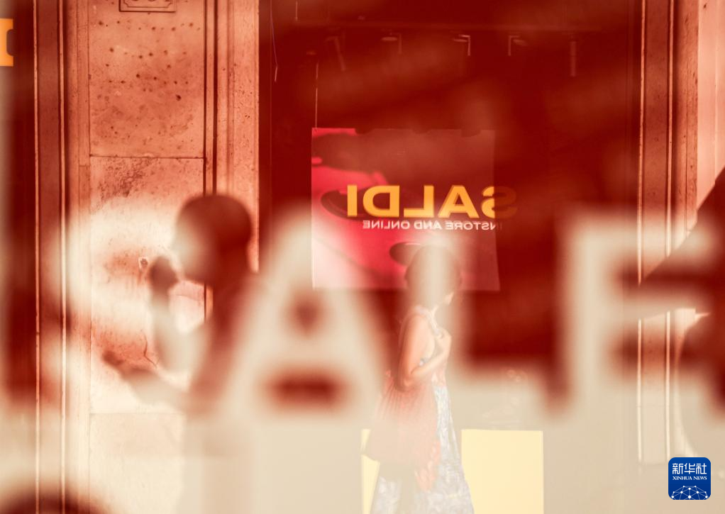7月5日，在意大利羅馬，人們經(jīng)過一處商店櫥窗。新華社記者 李京 攝