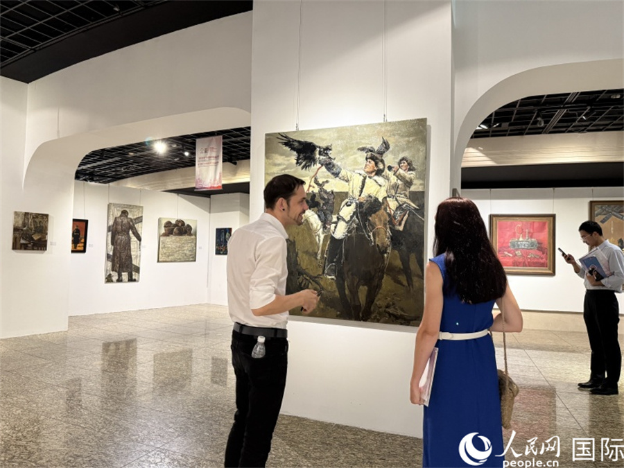 俄羅斯藝術(shù)家在展區(qū)欣賞畫作。人民網(wǎng)記者 楊倩攝