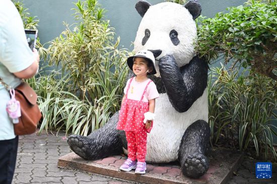 5月17日，在馬來西亞吉隆坡的國家動物園，一名小女孩與大熊貓雕塑合影。新華社記者 程一恒 攝